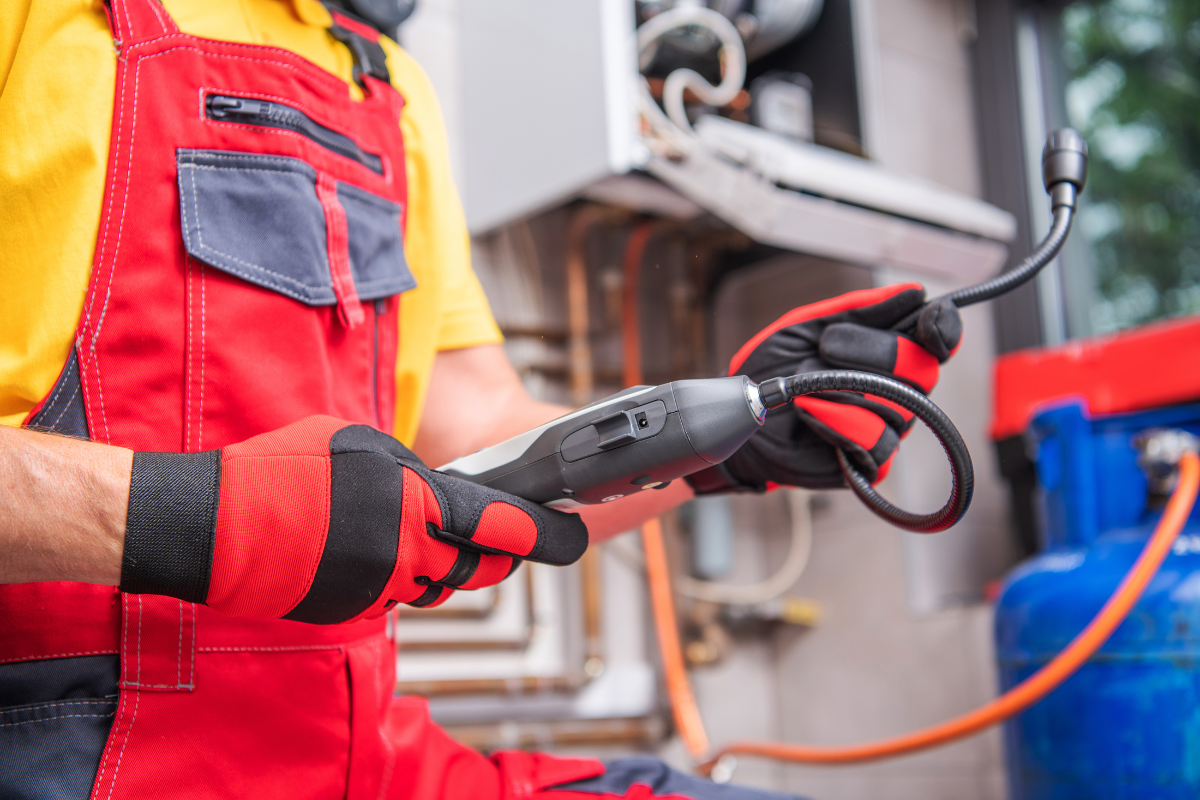 RKI gas detection equipment in use by a heating technician wearing red overalls and work gloves